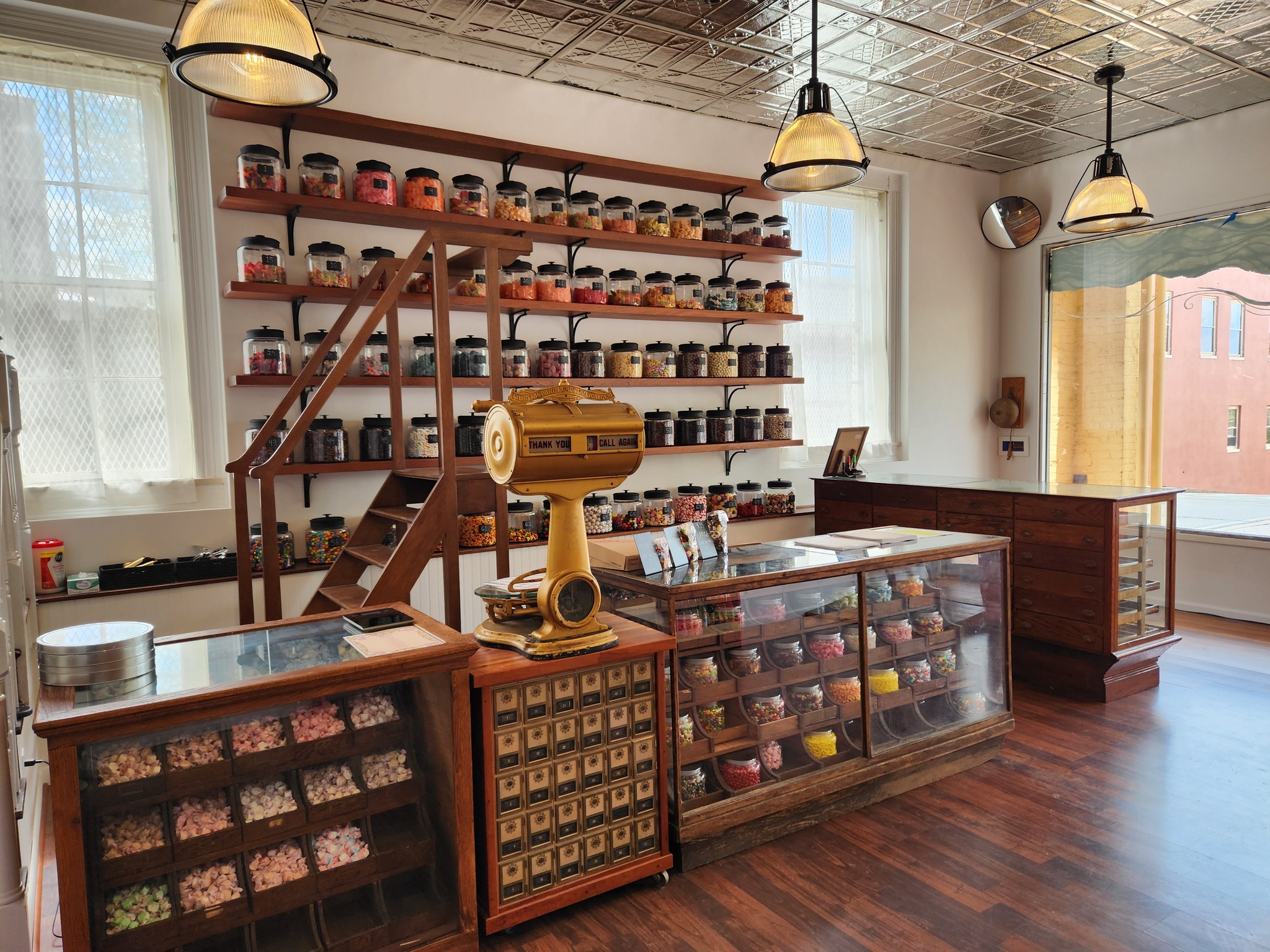 The Pop & Candy Shop interior with wooden shelves of glass jars beneath a tin ceiling